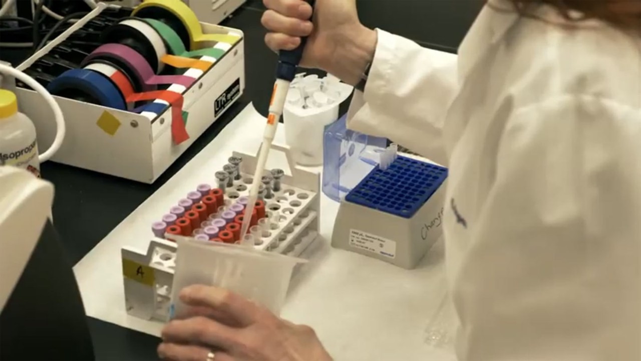 Medical technician wearing lab coat filling vials at desk