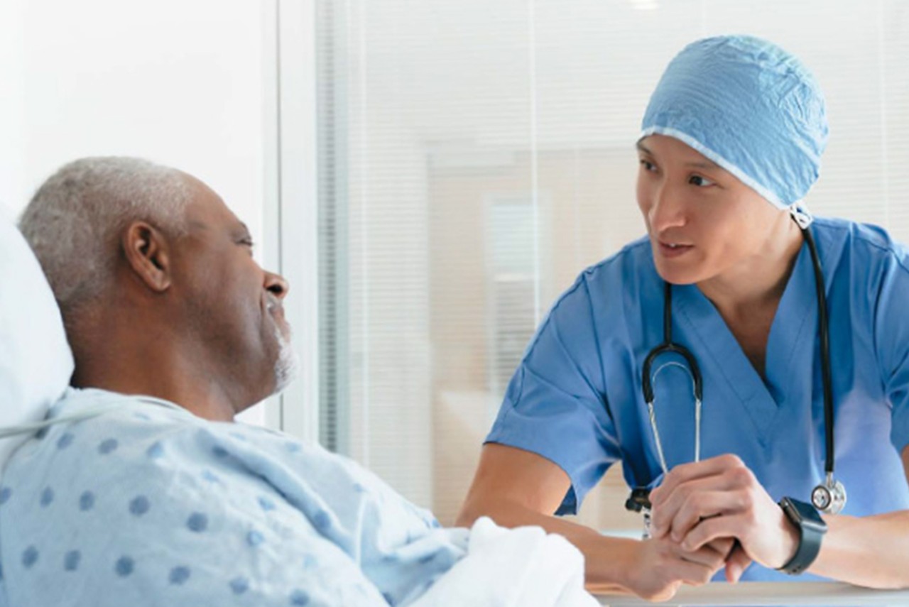 Healthcare professional talking to patient on hospital bed