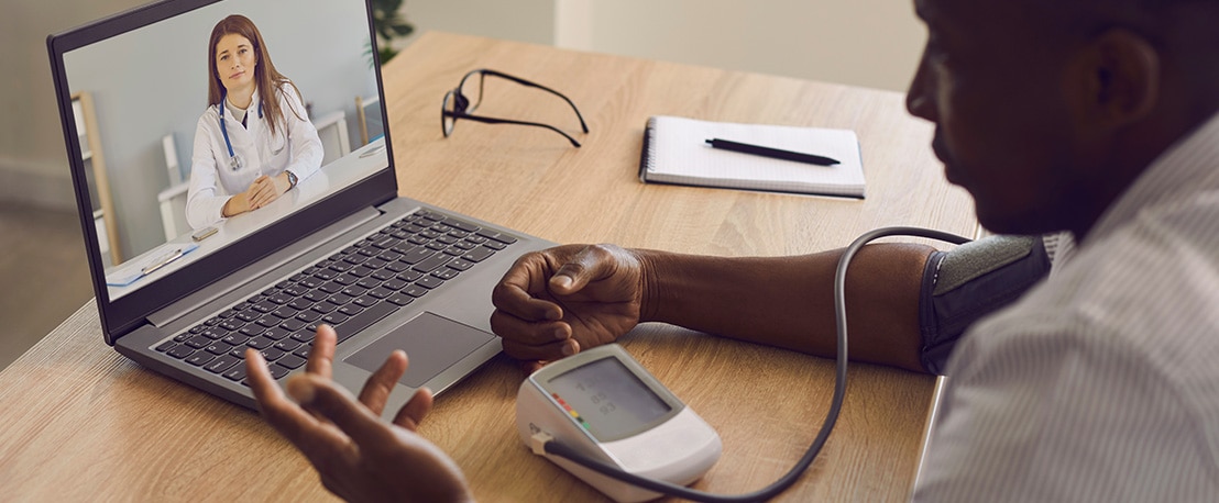 man with hypertension measures high blood pressure using sphygmomanometer during webcam telemedicine teleconference with online doctor