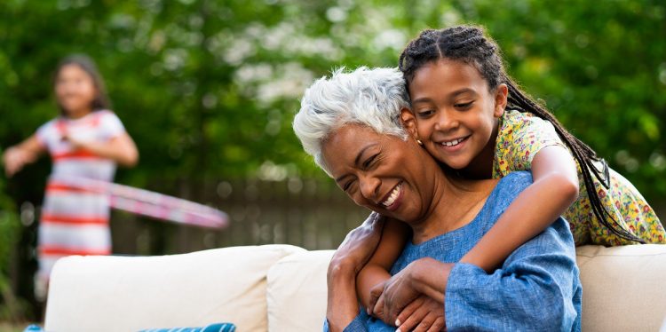 Young adult hugging mature adult outside in backyard