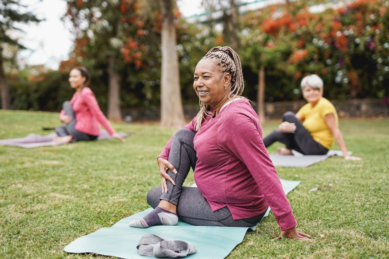 Multiracial women doing yoga exercise with social distance for coronavirus outbreak at park outdoor - Healthy lifestyle and sport concept; 