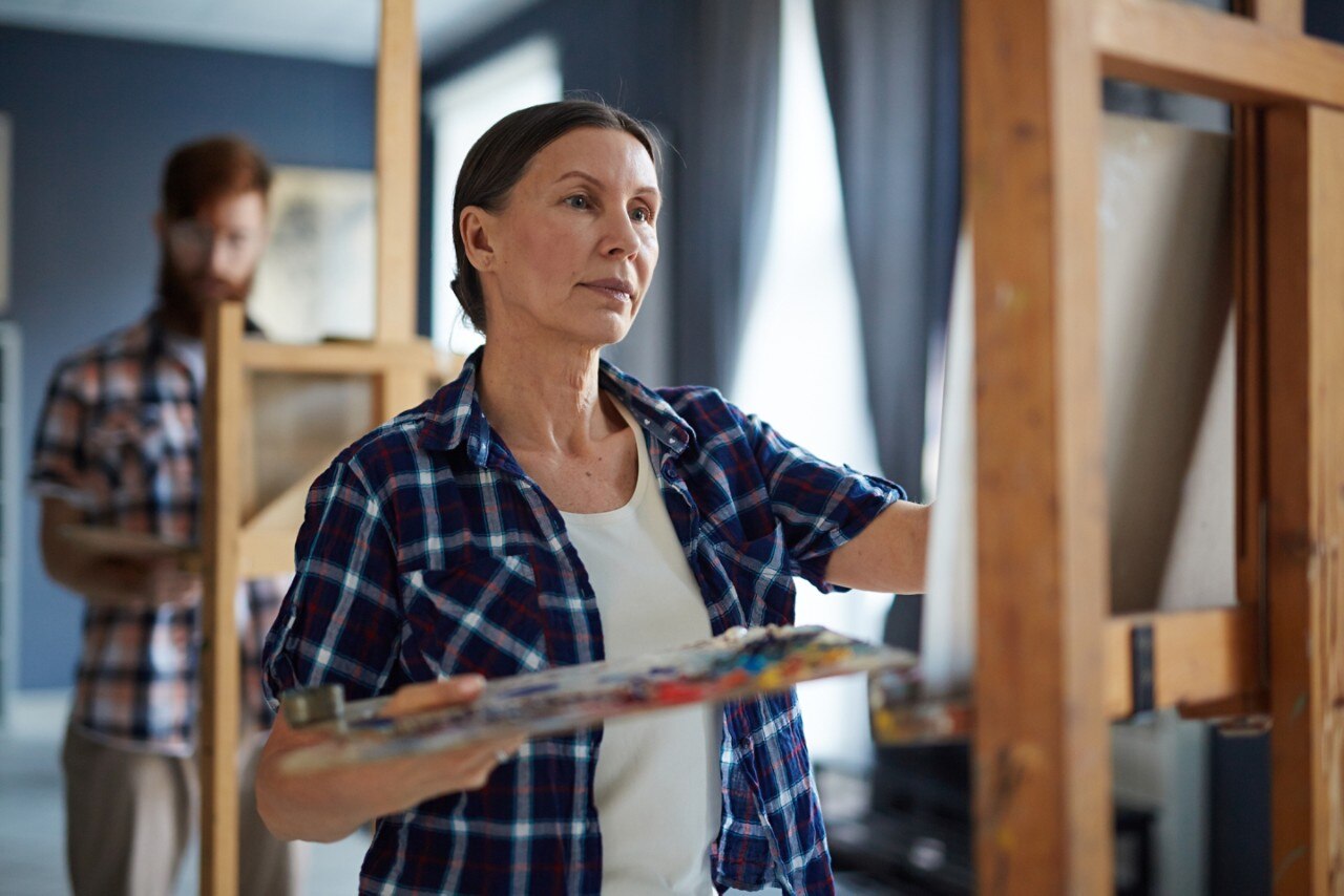 Portrait of elegant mature woman painting picture on easel standing in row of students in art class; Shutterstock ID 638774581; purchase_order: WPD2022; job: Neuromodulation (DBS); other: For social posts and landing page. 