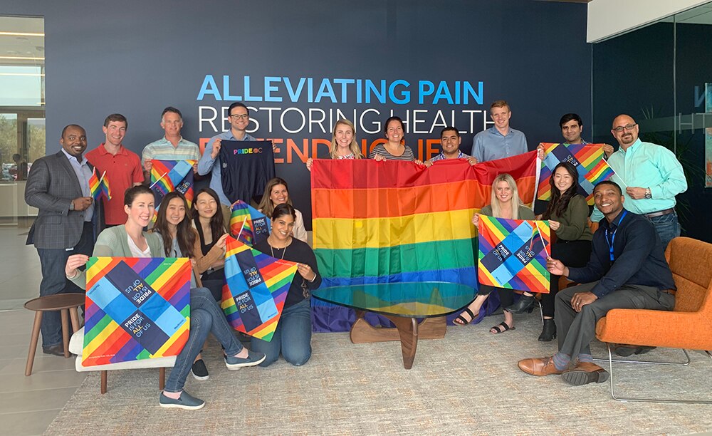 A photo of a group of Medtronic inside the front office holding Pride flags