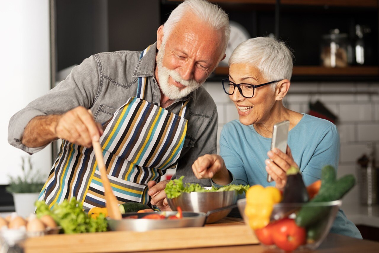 Modern and harmonious couple prepares their favorite recipe and shares with their friends via video call, fun and domestic life of pensioner; 
