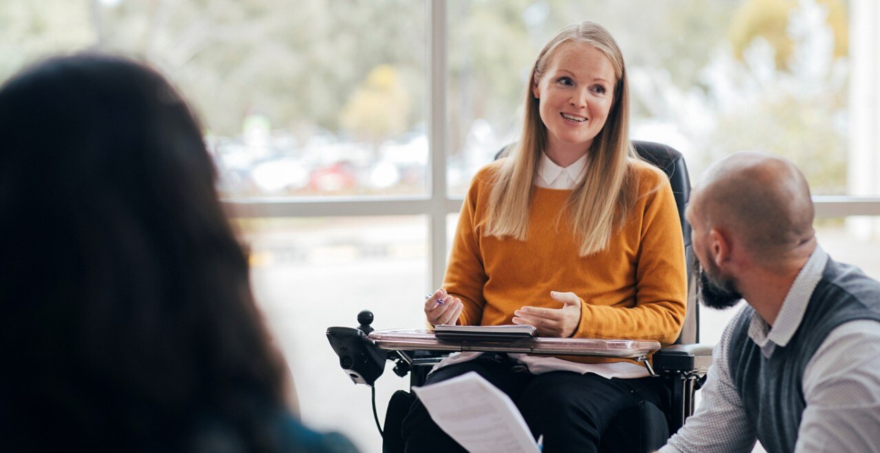 Woman in wheelchair holding a meeting with others