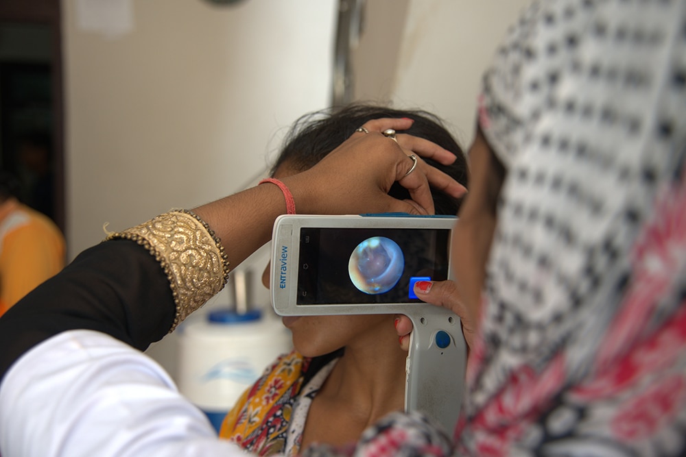 A photo of a woman sitting getting ear examined with camera