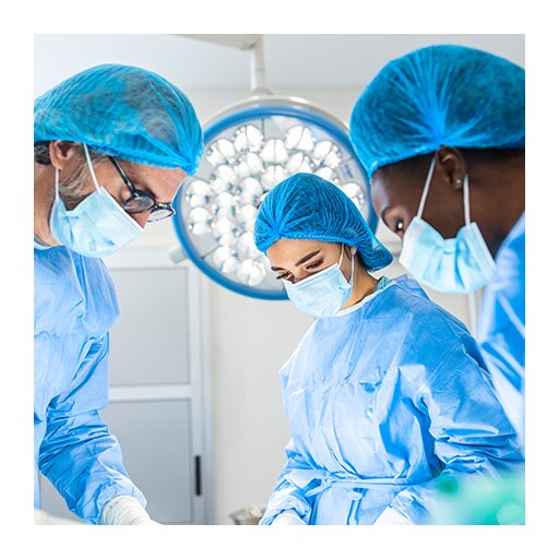 Three surgeons look down at their work