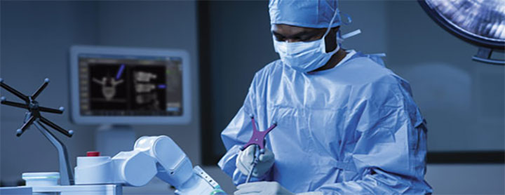 Male surgeon being assisted by a robotic instrument while performing an operation.