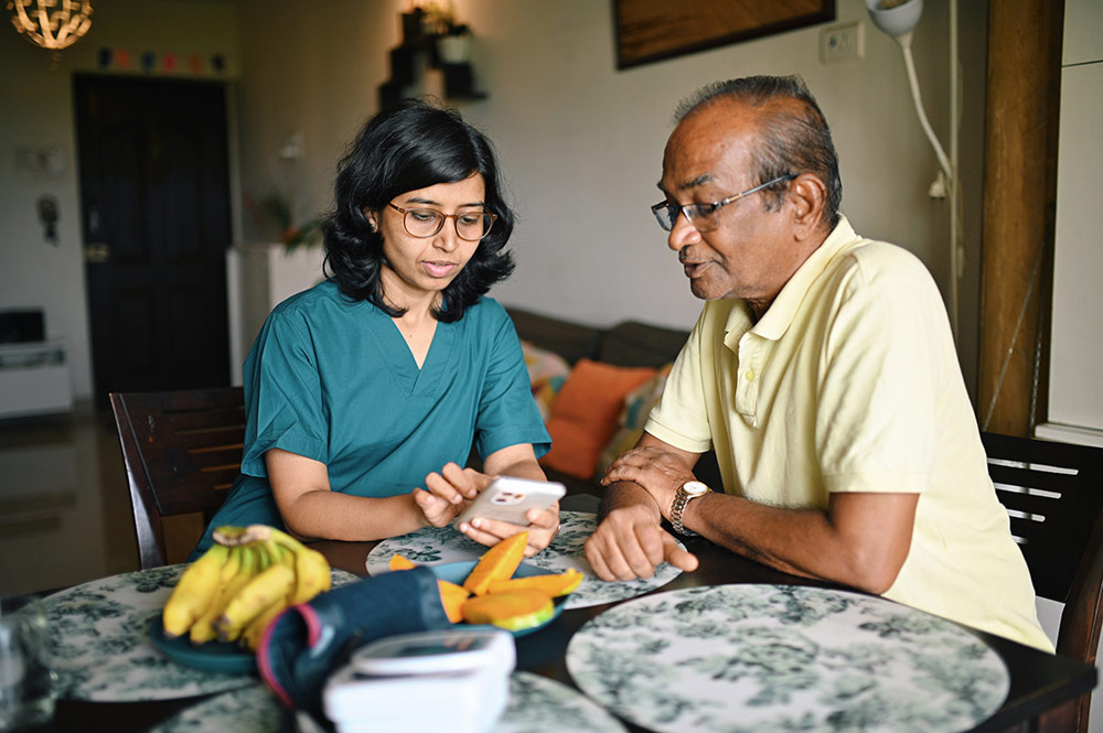 Photo of a healthcare worker talking with a man at a kitchen table.