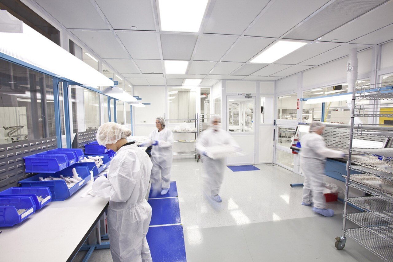 Several lab employees working inside lab dressed in blue scrubs